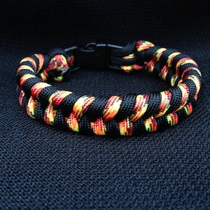 May include: A black, red, and yellow paracord bracelet with a black buckle closure.