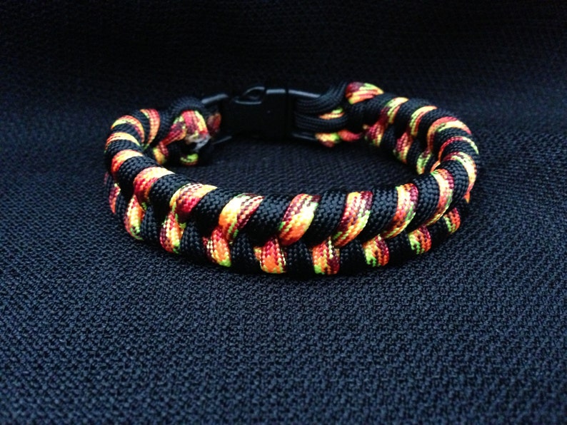May include: A black, red, and yellow paracord bracelet with a black buckle closure.