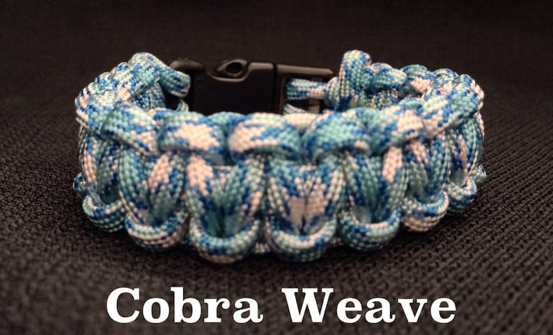 May include: A blue and white paracord bracelet with a black plastic clasp. The bracelet is woven in a cobra weave pattern. The text "Cobra Weave" is printed below the bracelet.