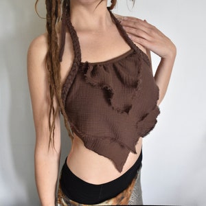 May include: A brown halter top with a ruffled neckline and a frayed edge. The top is made of a soft, lightweight fabric and has a relaxed fit.