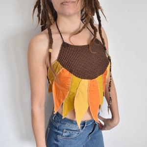 Peut inclure: Un haut halter brun et noir avec un motif de tournesol. Le haut est fait de diff&eacute;rents tissus dans des tons de jaune, orange et brun. Le haut est court et a une coupe d&eacute;contract&eacute;e.
