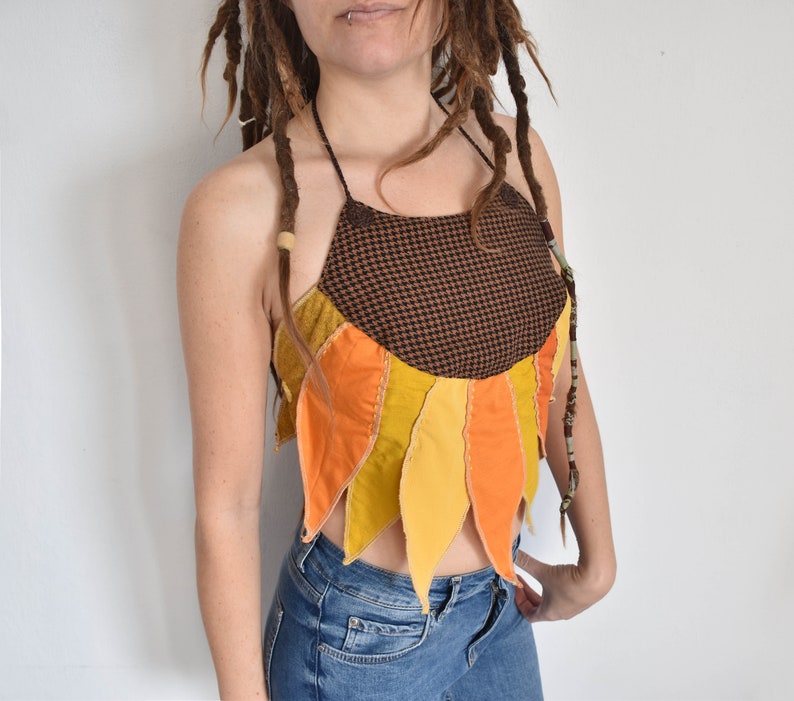 Peut inclure: Un haut halter brun et noir avec un motif de tournesol. Le haut est fait de diff&eacute;rents tissus dans des tons de jaune, orange et brun. Le haut est court et a une coupe d&eacute;contract&eacute;e.