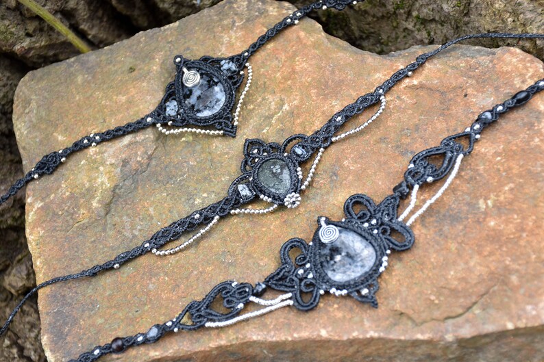 May include: Three black macrame necklaces with silver beads and clear quartz stones. Each necklace features a different design and stone.