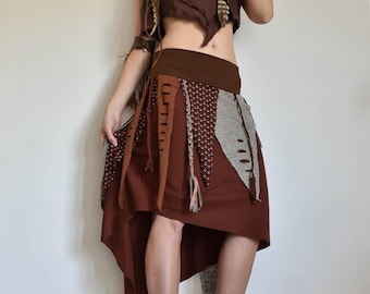 Peut inclure: Une jupe asymétrique marron avec des couches de tissu et des détails de franges. La jupe est faite de divers matériaux, dont le coton et le lin. La jupe est conçue pour être portée avec un haut ou une tunique.