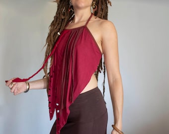 May include: A red halter top with a layered, asymmetrical design. The top is made of a soft, flowing fabric and has a relaxed, bohemian style.