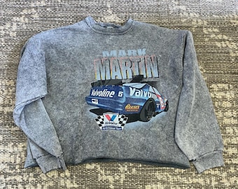 May include: A gray, distressed, long-sleeved sweatshirt with a vintage-style graphic of a race car. The car is blue and white with the text "Valvoline" and "Reese's" on it. The text "Mark Martin" is printed above the car.