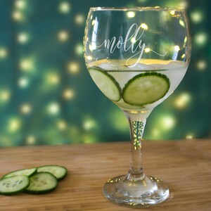 Könnte beinhalten: Ein personalisiertes Gin-Glas mit dem Namen "molly" auf der Seite. Das Glas ist mit Gin Tonic und Gurkenscheiben gefüllt.