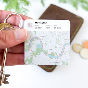 May include: A white keychain with a map of a running route. The map shows a route along the Thames River in London, England. The text on the keychain reads "Morning Run", "Distance 26.3 km", "Elev Gain 78 m", and "Time 2h 30m".