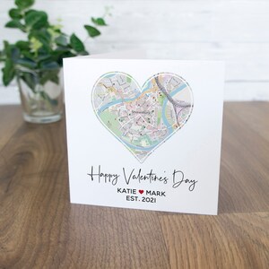 Può includere: Un biglietto bianco con una mappa di Shrewsbury, in Inghilterra, a forma di cuore. Il testo "Happy Valentine's Day" è scritto in corsivo nero. Sotto la mappa, il testo "KATIE ♥ MARK EST. 2021" è scritto in nero.