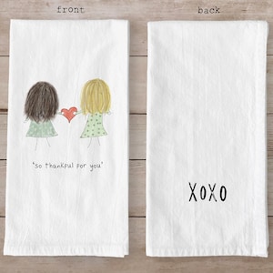 May include: White kitchen towel with a drawing of two figures holding a red heart, with the text "so thankful for you." The back of the towel has the text "XOXO."