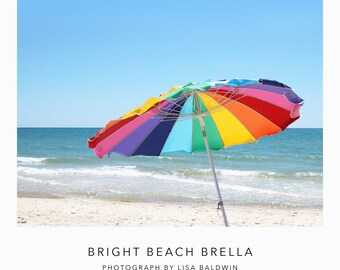 Foto de sombrilla de playa brillante con rayas de colores ondeando en la brisa del océano