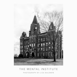 May include: A black and white photograph of a large brick building with a tall tower. The building has many windows and a large arched entrance. A bare tree stands in front of the building.