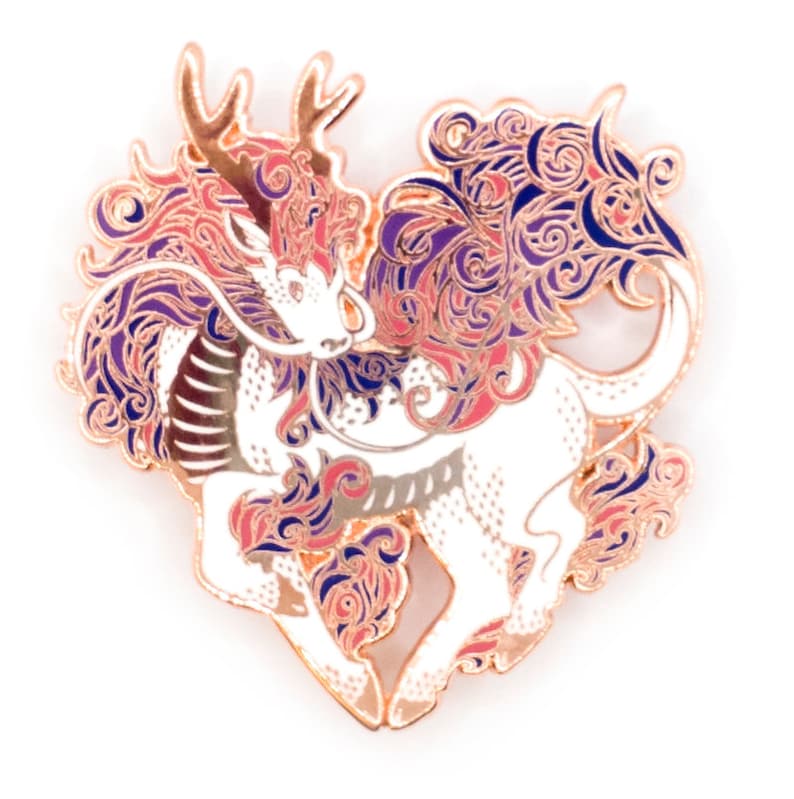 May include: Rose gold enamel pin featuring a white mythical creature with antlers, a long tail, and intricate swirling patterns in shades of pink, purple, and blue.