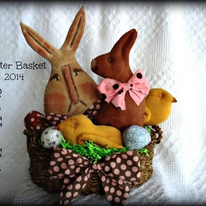 Könnte beinhalten: Ein brauner Weidenkorb gefüllt mit Osterschmuck, darunter zwei braune Hasen, ein gelbes Küken und bunte Eier. Der Korb ist mit einer rosa-braunen Schleife mit weißen Punkten verziert. Der Text "Easter Basket 2014" und "Click Your Heels" ist auf dem Bild zu sehen.