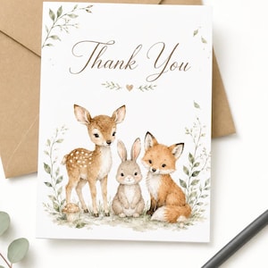 May include: A white greeting card with the text Thank You in brown script, featuring a watercolor illustration of a fawn, a rabbit, and a fox sitting together among green foliage and a small mushroom, accompanied by a brown envelope.