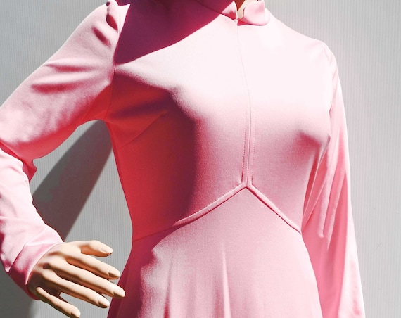 Long pink dress with sleeves and high collar, mod 70s fashion style.