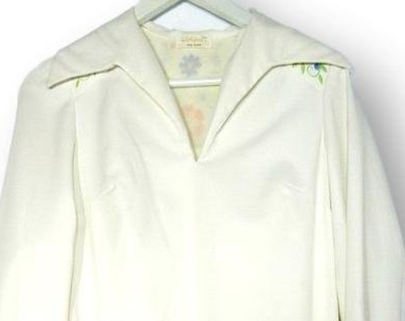 White dress with orange embroidery floral designs.