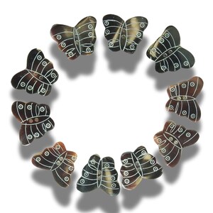 Peut inclure: Dix boutons en forme de papillon brun et blanc avec un motif décoratif. Les boutons sont disposés en cercle.