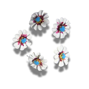 Può includere: Cinque orecchini a forma di fiore di margherita bianca con centri turchesi e accenti rosa. I petali sono bianchi con una leggera curva e il centro ha un anello color oro attorno alla pietra turchese. Su sfondo bianco.