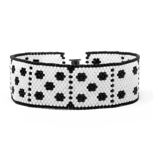 May include: A black and white beaded bracelet with a geometric pattern. The bracelet is made of small, round beads and has a clasp closure.