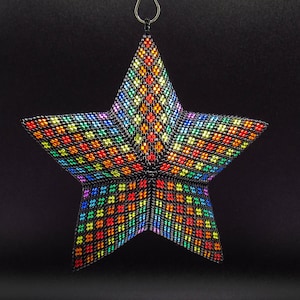 May include: A rainbow-colored beaded star ornament with a black background. The star is made of small, colorful beads that are arranged in a geometric pattern.
