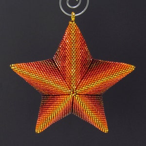 May include: A beaded star ornament in shades of red, orange, and gold. The star is made of small, tightly woven beads and has a metallic gold finish.