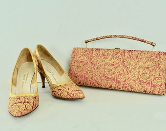 May include: A pair of red and gold high-heeled shoes with a matching clutch purse. The shoes and purse are covered in a brocade fabric with a floral pattern.