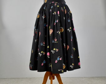 May include: A black midi skirt with a colorful print of various makeup items. The skirt is pleated and has a full silhouette.