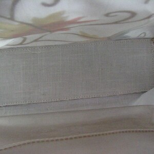 May include: The inside of a white fabric tote bag with a light gray fabric lining. The lining has a stitched edge.