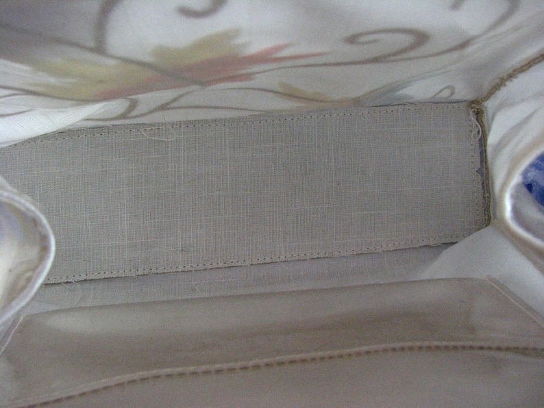 May include: The inside of a white fabric tote bag with a light gray fabric lining. The lining has a stitched edge.