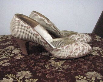 May include: A pair of white mesh high-heeled shoes with brown trim. The shoes have a delicate, feminine design.