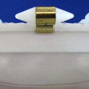 May include: White plastic clutch purse with a gold metal clasp and the words "Original Blanche" printed on the inside.