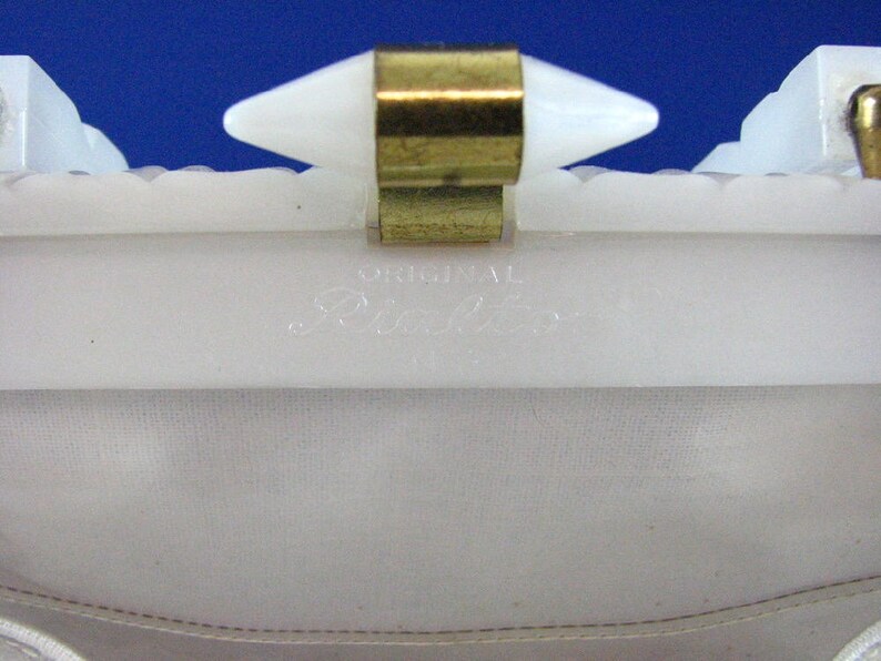 May include: White plastic clutch purse with a gold metal clasp and the words "Original Blanche" printed on the inside.