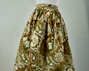 May include: A brown and green paisley print skirt with a gathered waistline. The skirt is pleated and has a full, flowing silhouette.