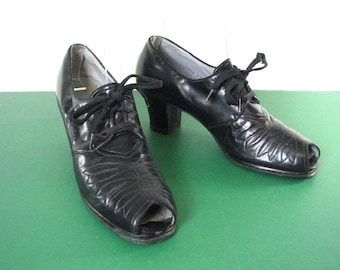 May include: A pair of black leather peep-toe shoes with a lace-up design and a low heel.