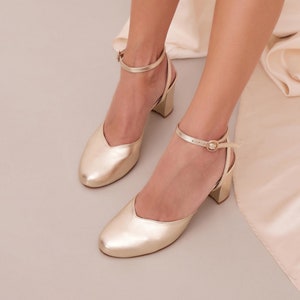 May include: Gold heeled shoes with ankle straps and a pointed toe.
