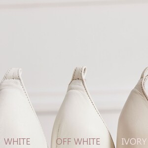 May include: Three pairs of white leather shoes, showing the back of the shoes. The shoes are labelled "WHITE", "OFF WHITE", and "IVORY" from left to right.