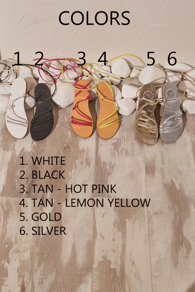 May include: Six pairs of sandals in different colours, labelled with numbers 1 through 6. The colours are white, black, tan with hot pink laces, tan with lemon yellow laces, gold, and silver.