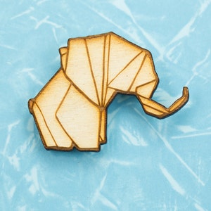 May include: A wooden origami elephant cutout, with a light brown colour, against a light blue background.
