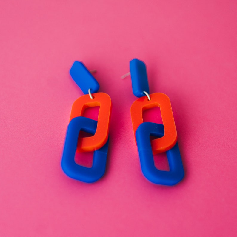 May include: A pair of blue and orange statement earrings with a chain link design.