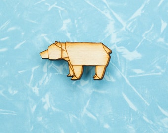 May include: A wooden bear figurine in a geometric origami style, with a light brown colour. The bear is standing on a light blue background.