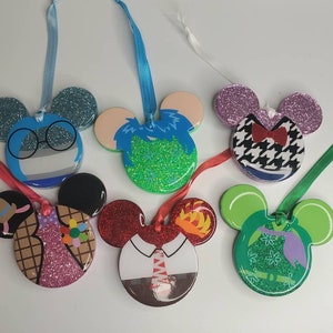 May include: Six glitter-covered Mickey Mouse-shaped ornaments with different designs. The ornaments are blue, green, pink, red, and white with various patterns and designs.