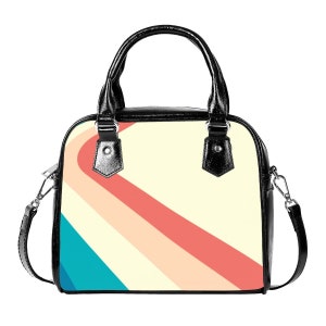 K&ouml;nnte beinhalten: Eine schwarze Handtasche mit einem Schultergurt. Die Handtasche hat ein Retro-Design mit einem diagonalen Streifenmuster in den Farben Rosa, Orange, Gelb und Blau.