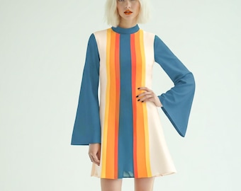 Könnte beinhalten: Ein kurzes Kleid mit ausgestellten Ärmeln und hohem Ausschnitt. Das Kleid zeigt ein vertikales Streifenmuster in den Farben Creme, Orange, Gelb und Blau, mit einfarbig blauen Ärmeln und einem cremefarbenen Grundstoff auf dem gesamten Kleid.