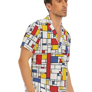 Puede incluir: Una camisa de manga corta con botones y un patr&oacute;n geom&eacute;trico en rojo, amarillo, azul y blanco. La camisa tiene cuello y un ajuste holgado.