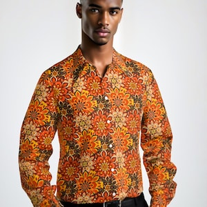 May include: A long-sleeved button-down shirt with a colorful, geometric pattern in shades of orange, yellow, and brown. The shirt has a collared neckline and a button closure.