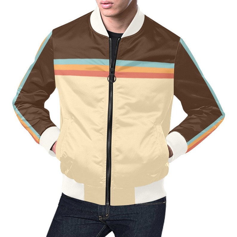 May include: A satin bomber jacket with a cream-colored body, brown upper section, and white cuffs and collar. The jacket features a horizontal stripe design in orange, blue, and yellow. The sleeves have a matching stripe design.