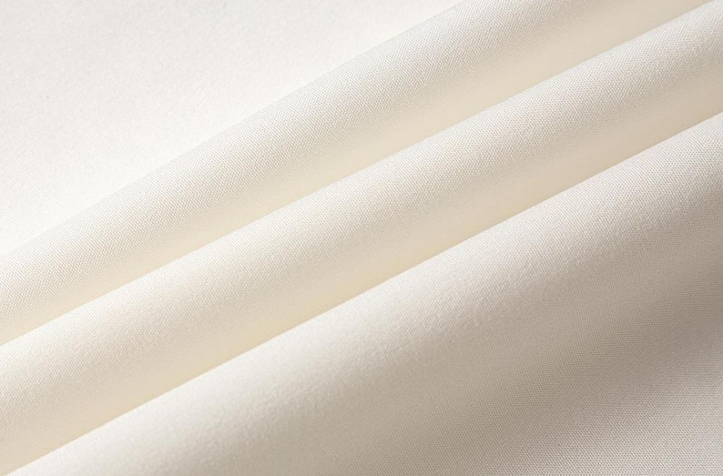 May include: Close-up of a smooth, white fabric with soft folds and wrinkles.