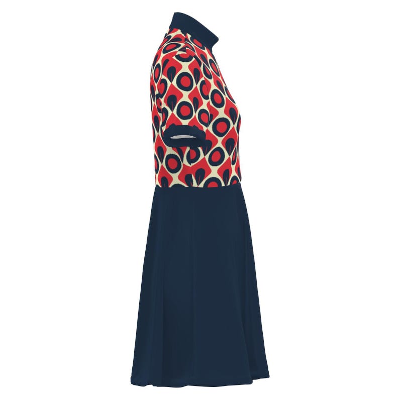 May include: A short-sleeved dress featuring a navy blue skirt and a patterned bodice. The bodice has a cream background with red circles and black accents. The dress has a high, navy blue collar and short sleeves with navy blue trim.