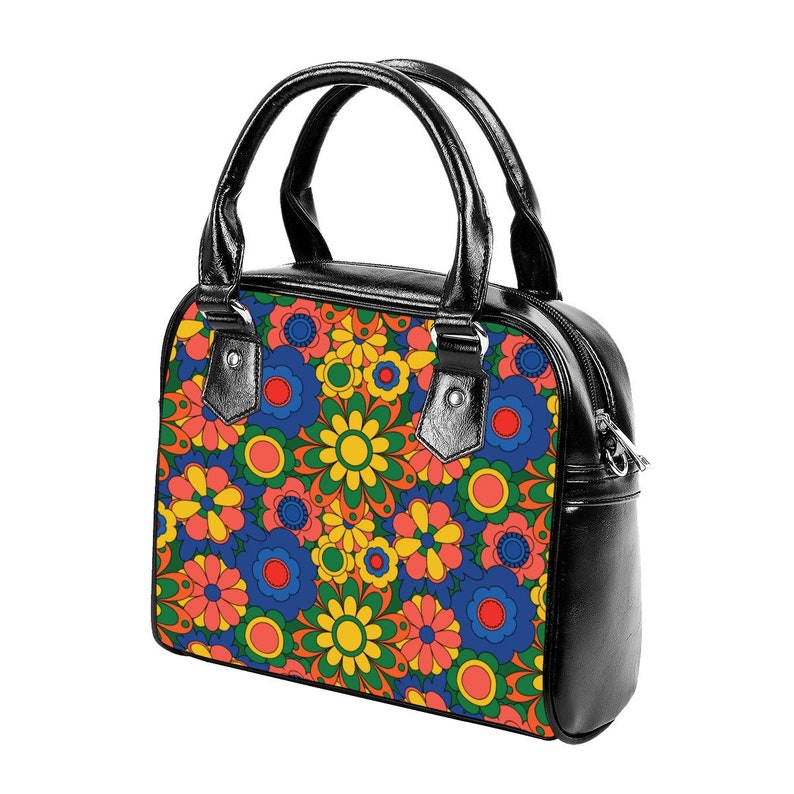 May include: A black handbag with a floral pattern. The pattern features colorful flowers in shades of red, orange, yellow, green, blue, and pink.